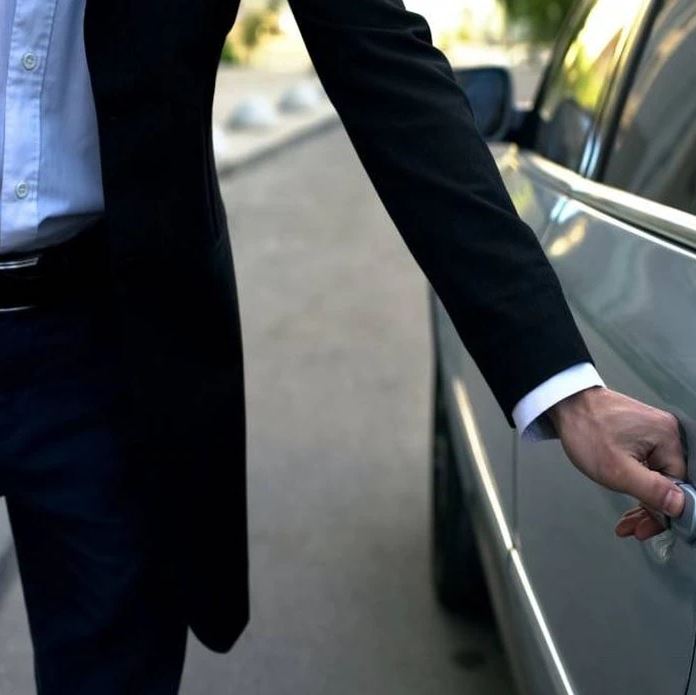 chauffeur de maitre ouvrant la porte d'une berline